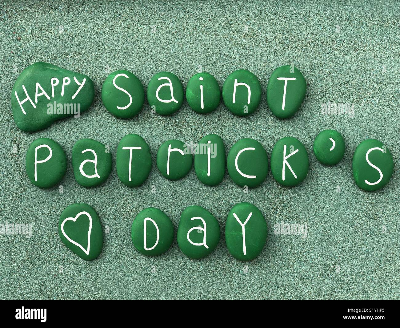 San Patrizio con verde pietre dipinte su sabbia verde Foto Stock