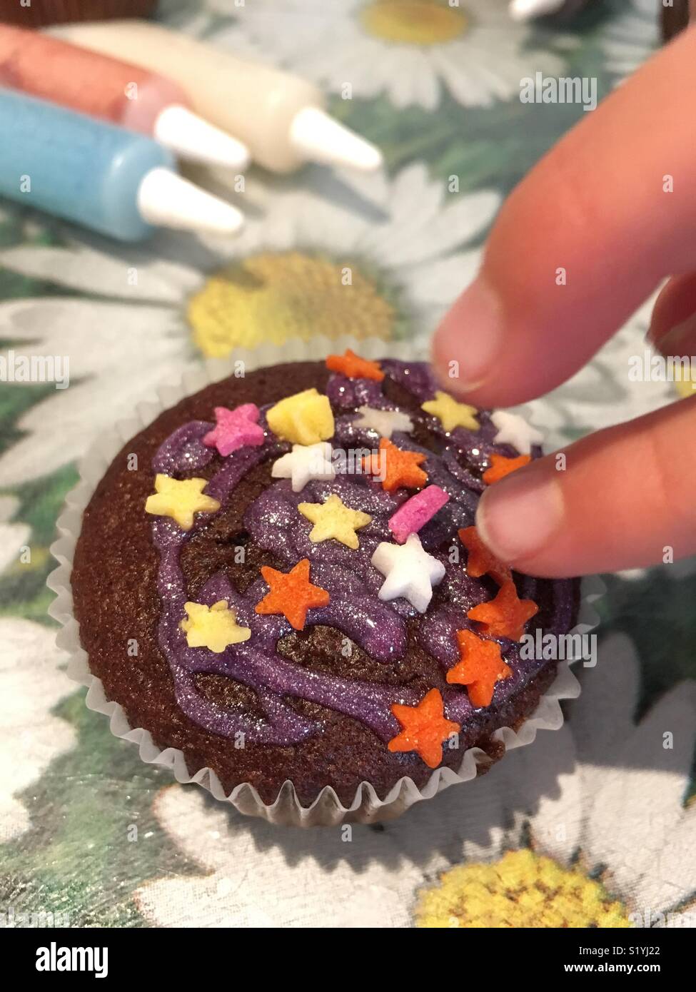 Un giovane ragazze dita decorare una tazza di cioccolato torta Foto Stock