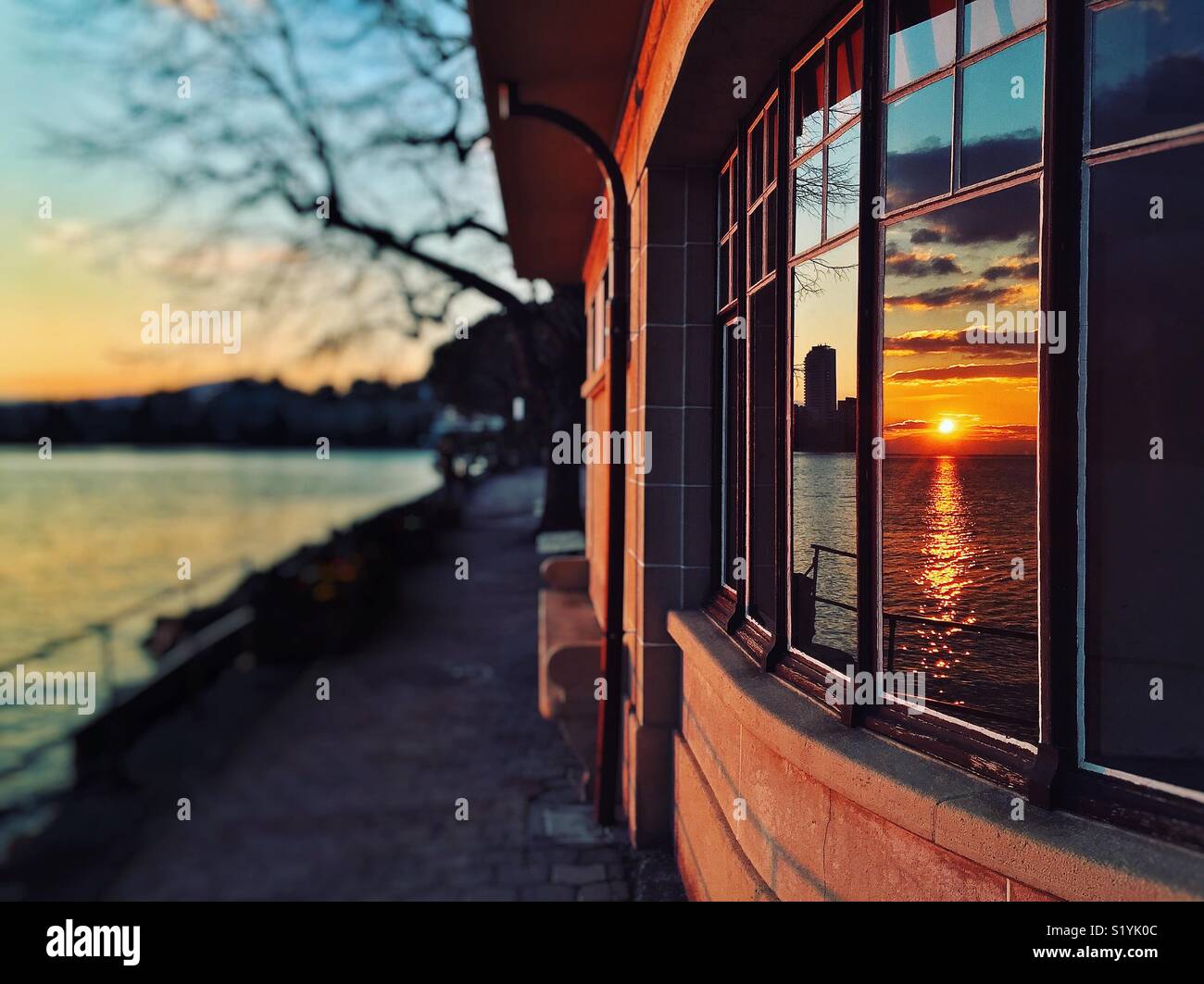 Tramonto sul lago di Ginevra riflessa nelle finestre di un edificio Art Deco Foto Stock
