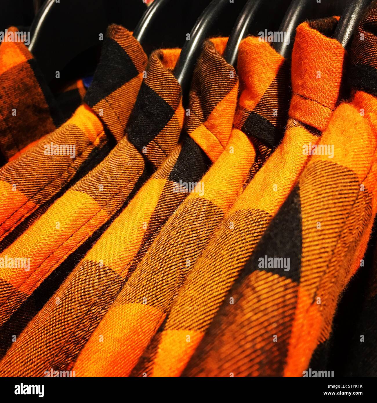 Rack di colore arancione, verificare lumberjack magliette sulle staffe. Foto Stock