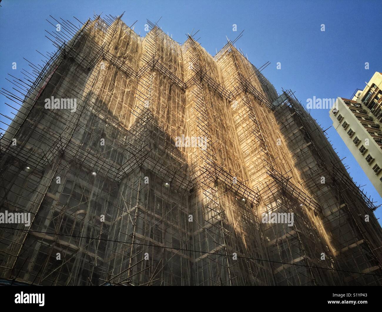 Un alto edificio residenziale di appartamenti coperti con bambù ponteggio a Wan Chai, Isola di Hong Kong - Immagine stock catturata con smartphone