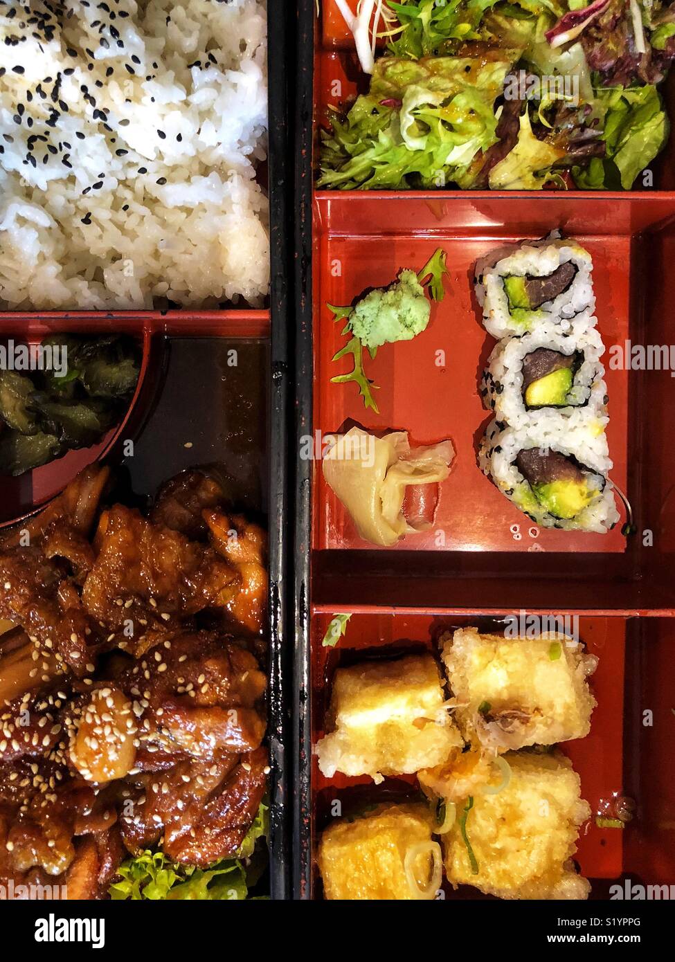 Un giapponese di bento scatola contenente sushi, riso e insalata di pollo con salsa. Foto Stock