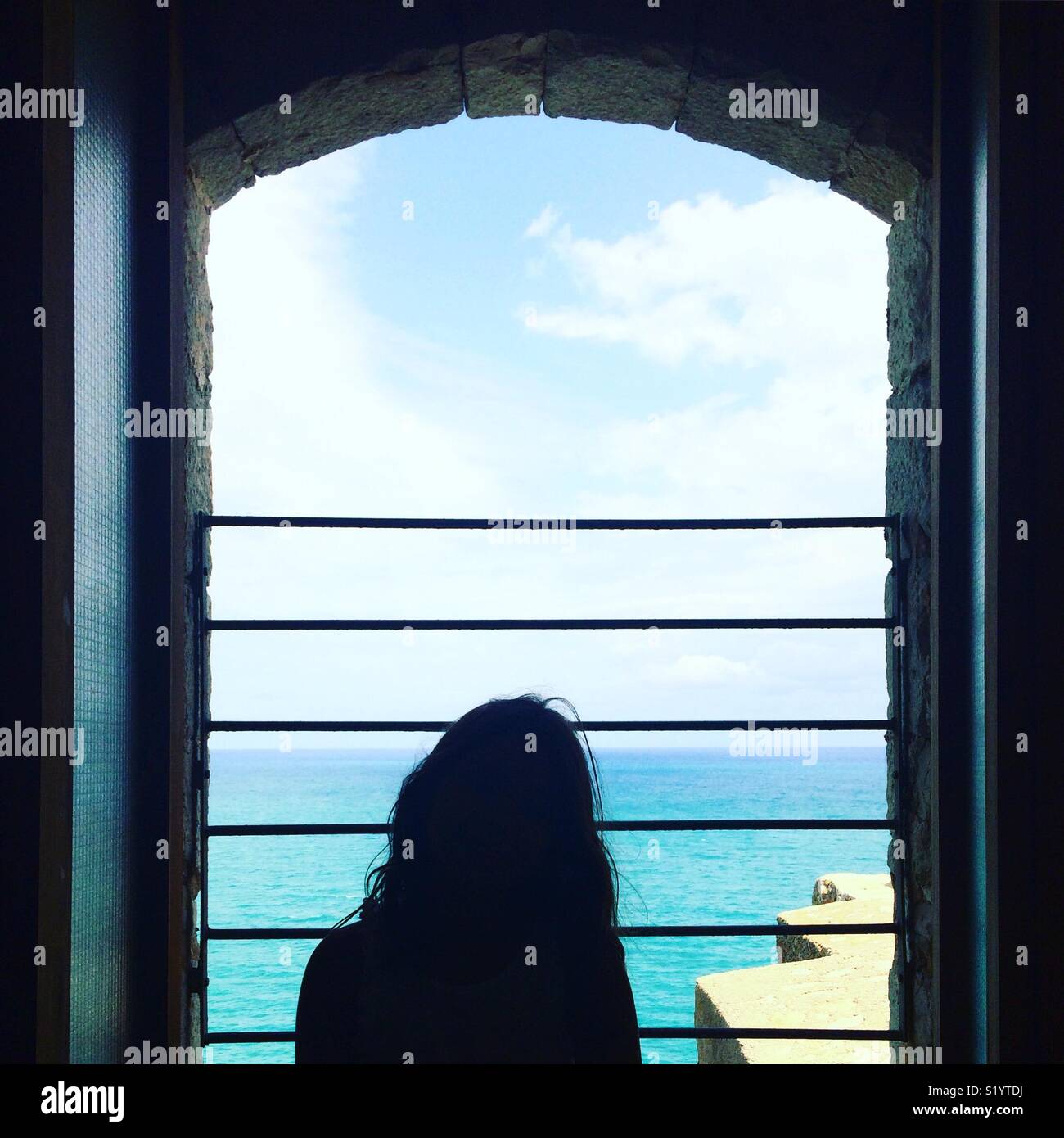 Ragazza guardando fuori dalla finestra sul mare Foto stock - Alamy