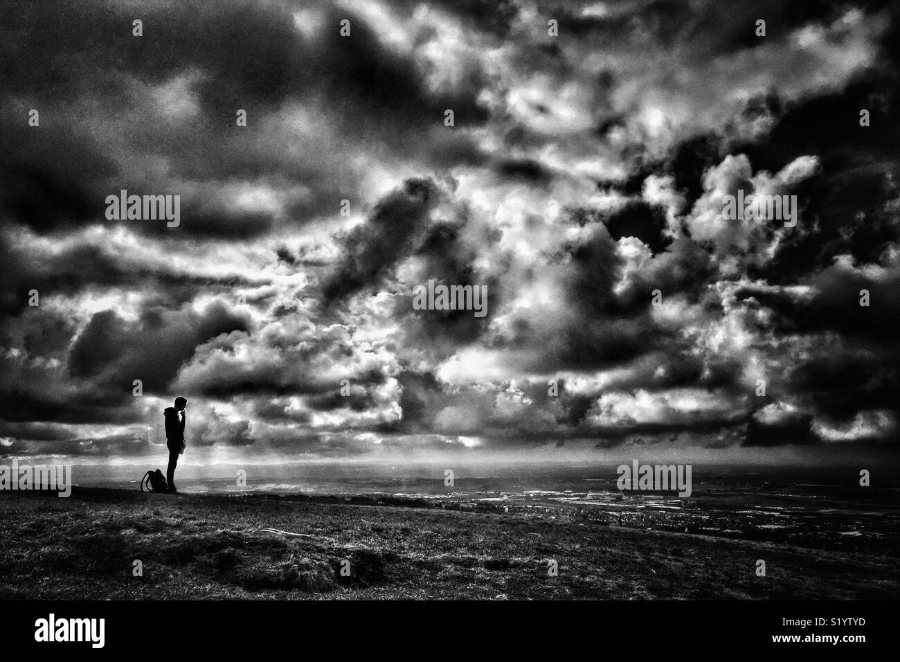 La figura in silhouette guardando a vista su Bolton dal vertice se Rivington Pike Foto Stock