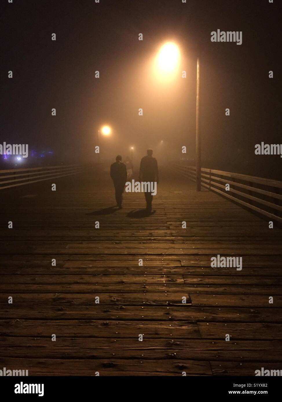 Parlando di una passeggiata sul molo su un molto notte di nebbia. Foto Stock