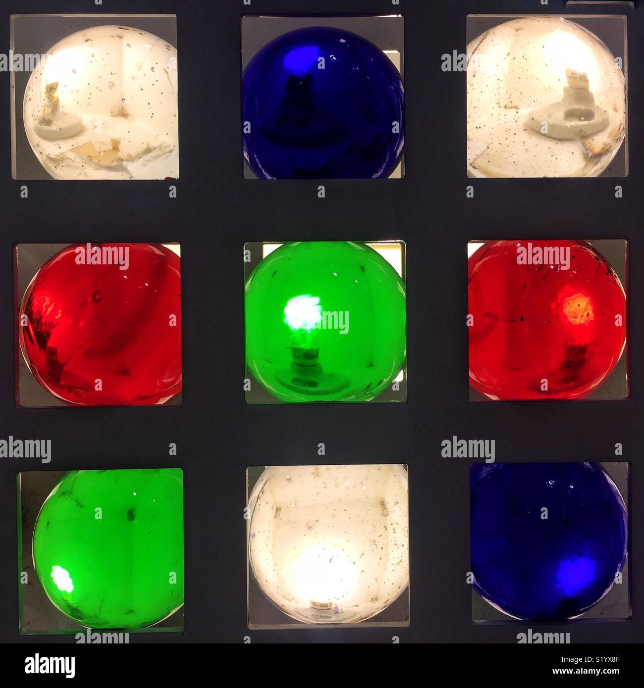 Rosso, bianco, blu e verde luci rotonde nella parete a griglia Foto Stock