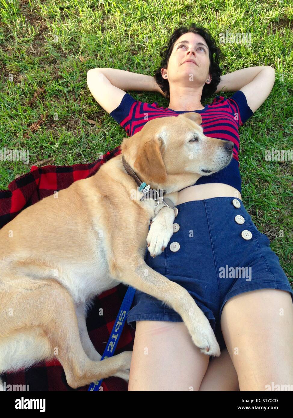 La donna e la sua Labrador retriever giacente sul suo su un tappeto picnic nel parco Foto Stock