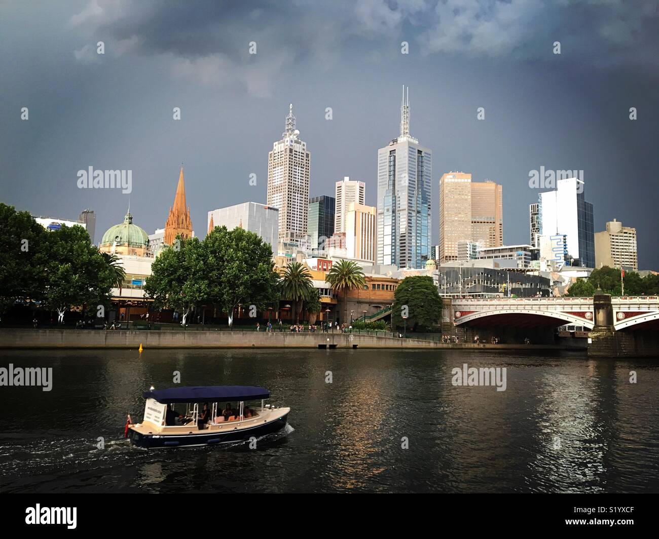 Lo skyline di Melbourne con una barca sul fiume Yarra durante le tempeste Foto Stock