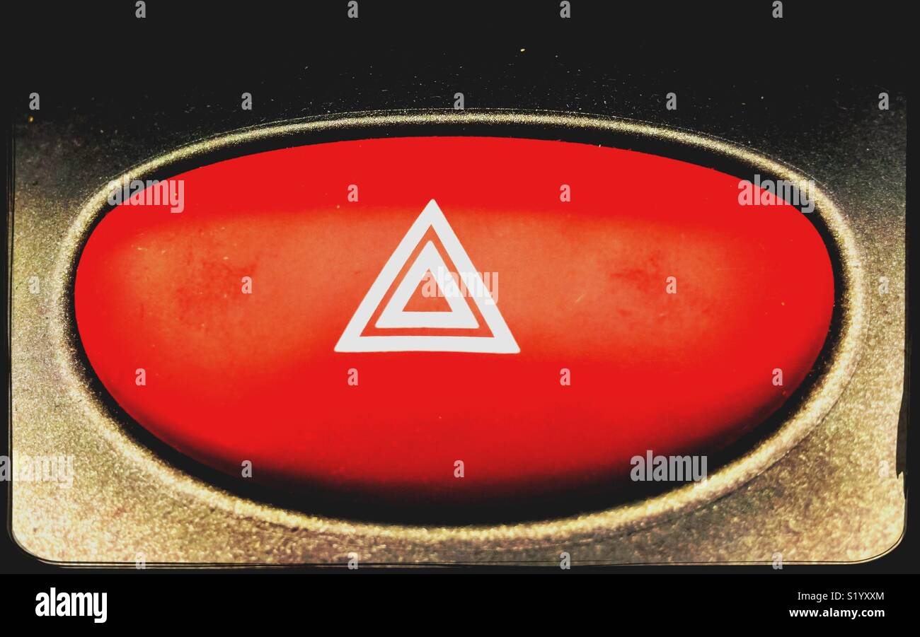Spia rossa pulsante con un doppio triangolo bianco sul suo centro su un cruscotto di automobile. Foto Stock