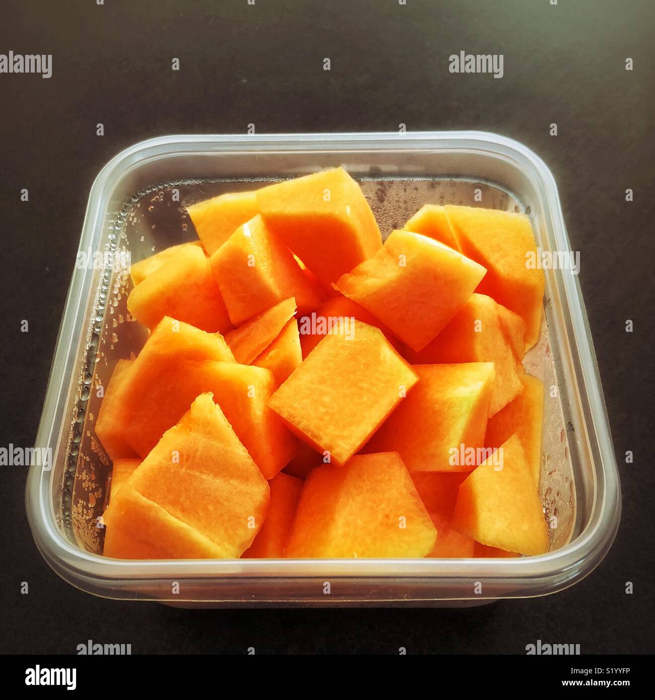 Plastica contenitore quadrato pieno di fresco tagliato pezzi di melone - Immagine stock catturata con smartphone