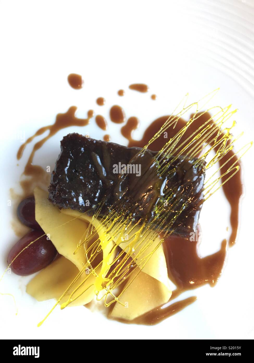 Presentato splendidamente dessert di sticky toffee pudding con spin decorazione di zucchero e di frutta - Immagine stock catturata con smartphone
