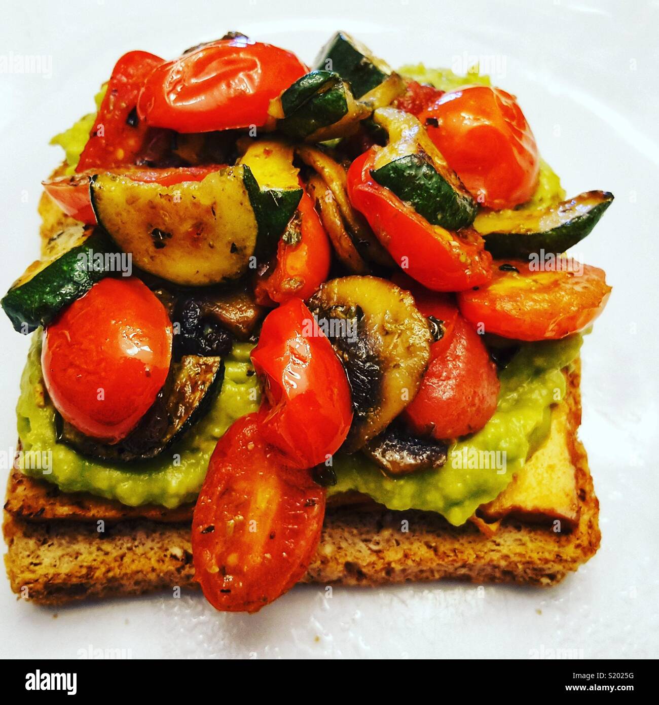 Vegan Avocado Toast con funghi tagliati a fettine, Pomodorini e Zucchine Zucchine Foto Stock