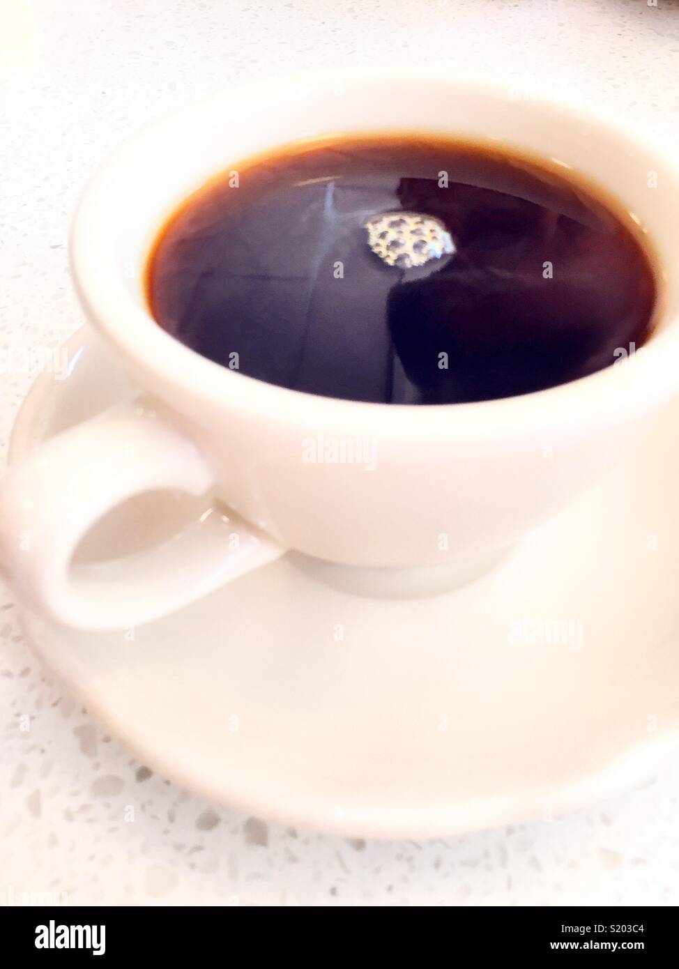 Caffè in un tutto bianco tazza e piattino su un tavolo da pranzo, STATI UNITI D'AMERICA - Immagine stock catturata con smartphone