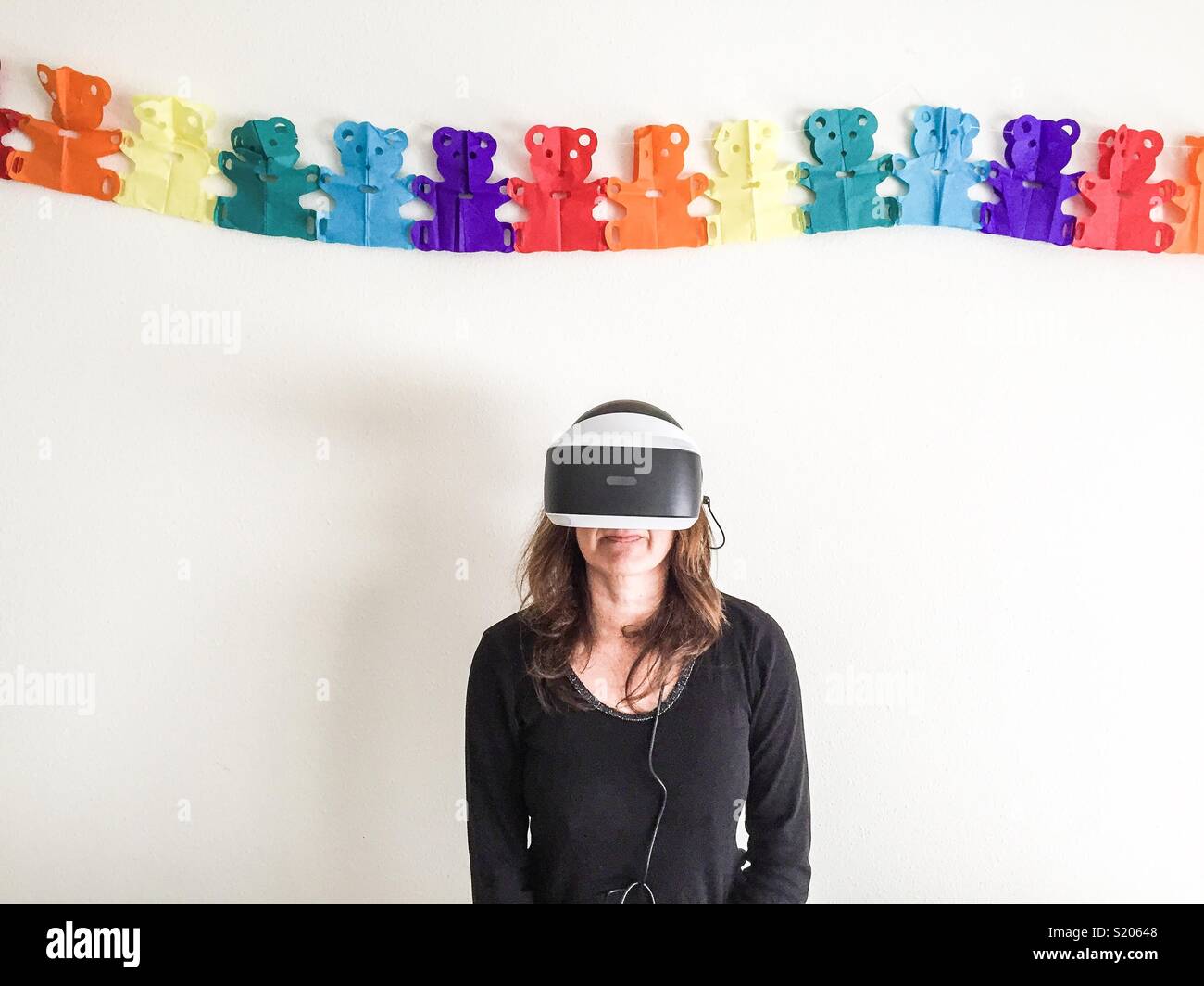 Donna con occhiali di realtà virtuale anteriore delle Nazioni Unite di una parete con orsetti di peluche Foto Stock