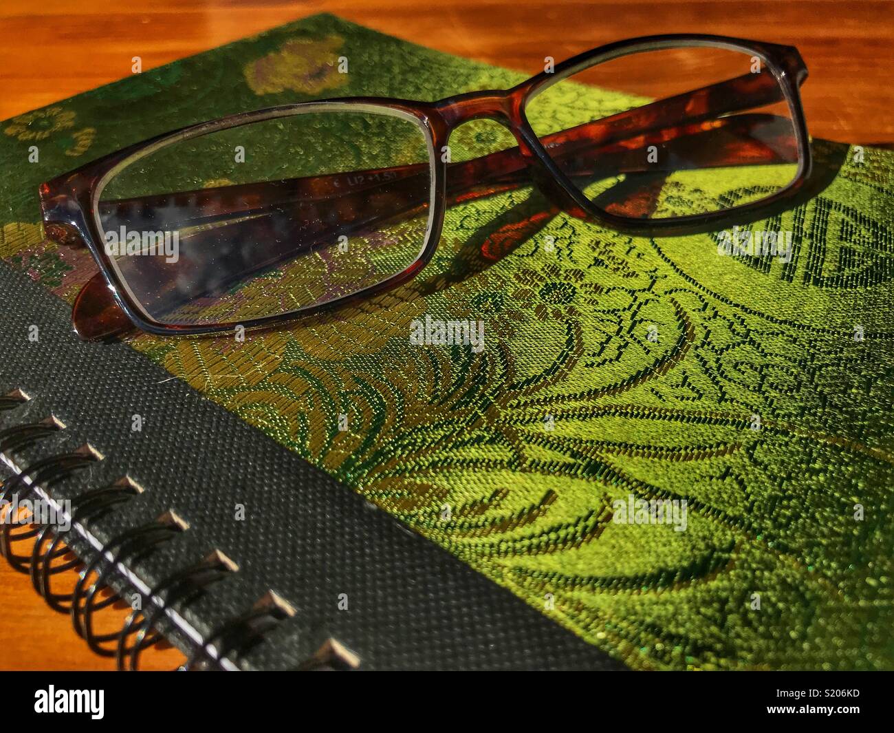 Occhiali su un tessuto verde coperto di notebook a spirale Foto Stock