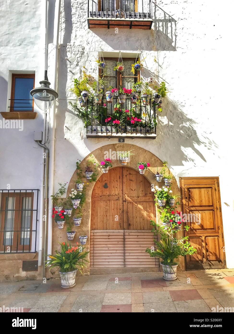 Una casa di città decorate con la fioritura per le piante in vaso intorno alla porta e sul balcone nella zona vecchia della città di Javea/ Xabia, Alicante, Spagna - Immagine stock catturata con smartphone
