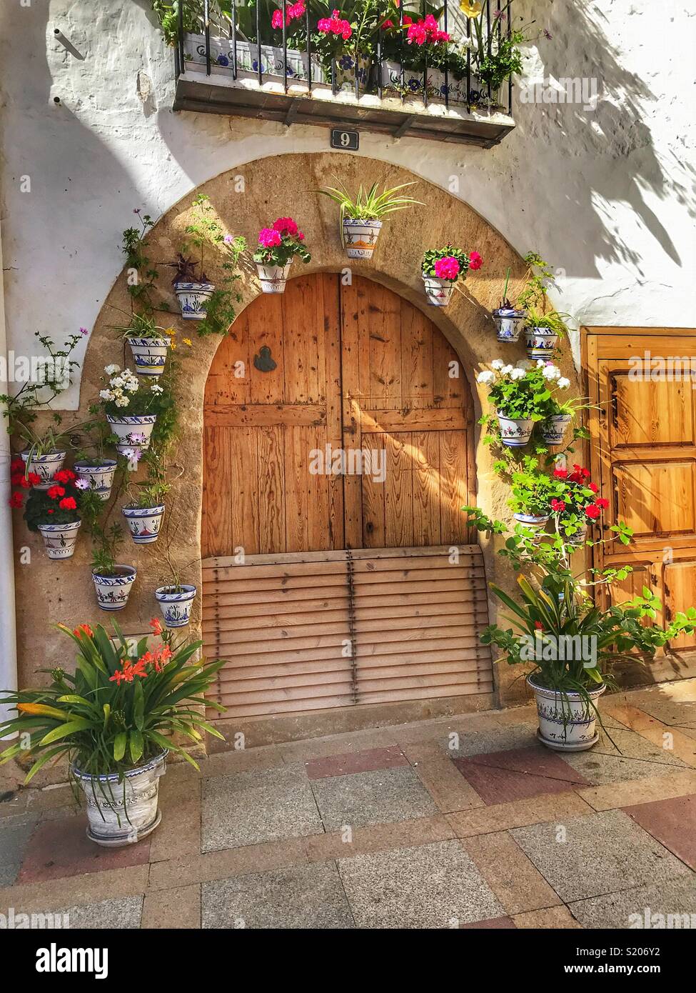 Una casa di città decorate con la fioritura per le piante in vaso intorno alla porta e sul balcone nella zona vecchia della città di Javea/ Xabia, Alicante, Spagna - Immagine stock catturata con smartphone
