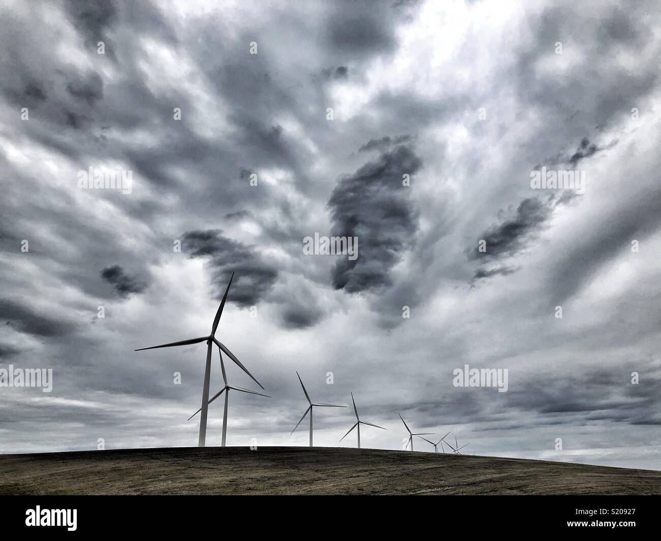 Fila di mulini a vento in Eastern Washington con drammatica sky Foto Stock