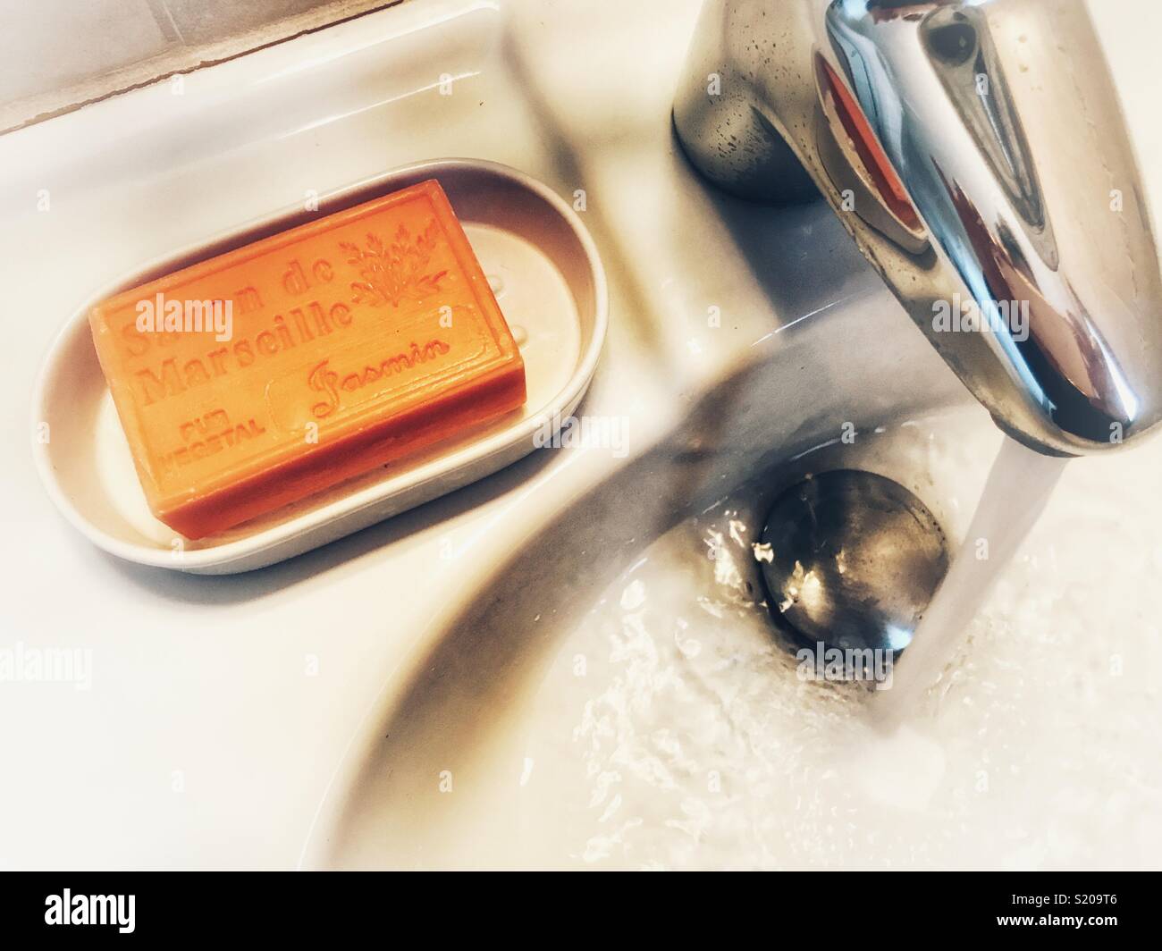 Provenza sapone in un portasapone e aprire il rubinetto con acqua in esecuzione in un lavabo bianco - Immagine stock catturata con smartphone