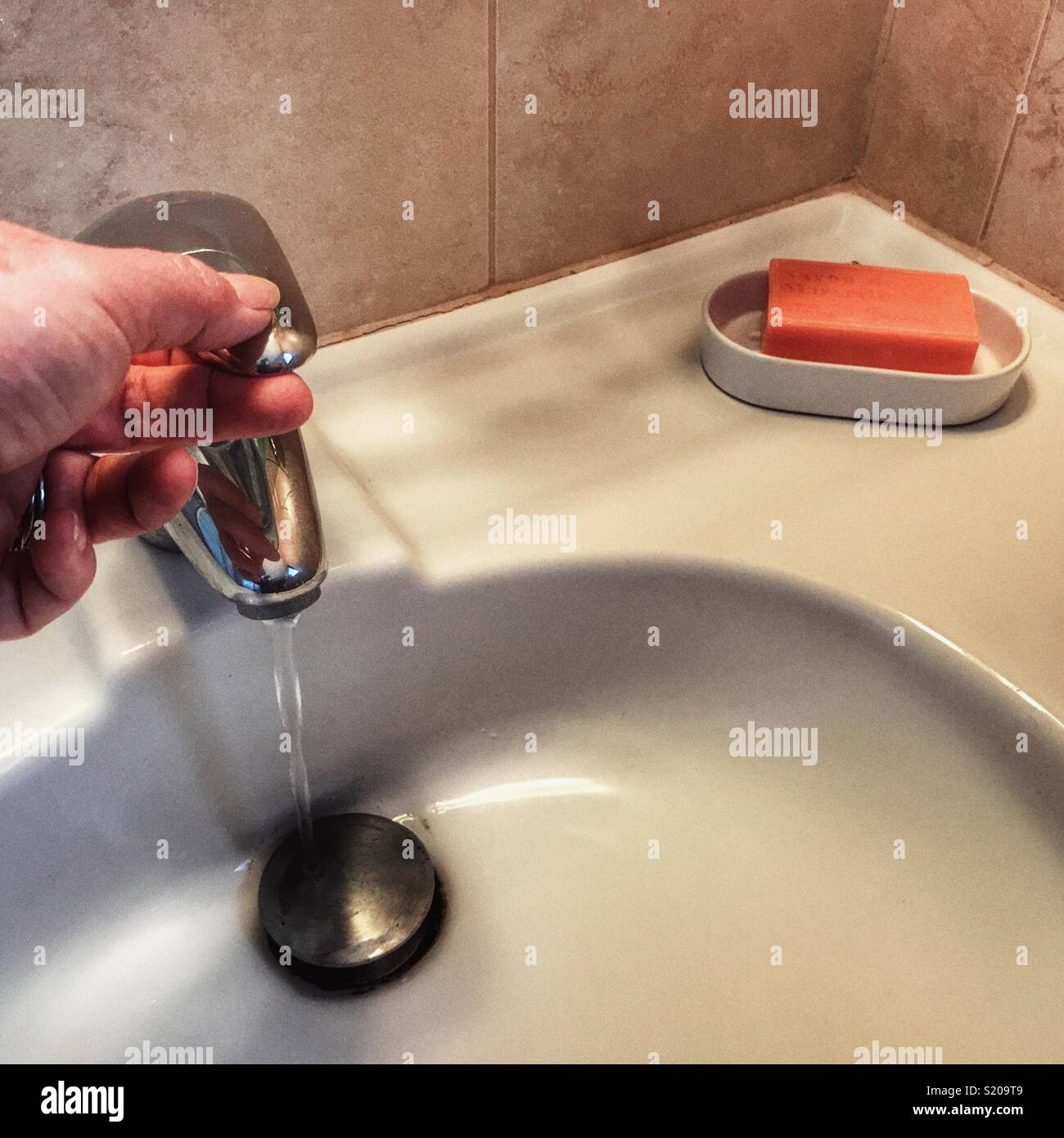 POV mano girando su bagno rubinetto, con acqua in esecuzione. Sapone in un portasapone sul lavandino. - Immagine stock catturata con smartphone