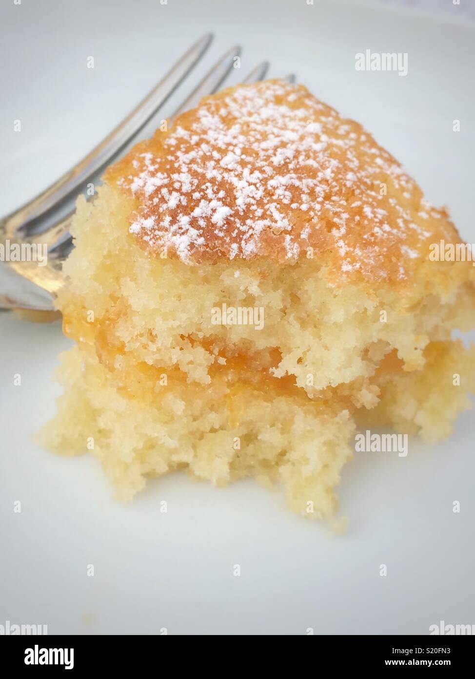 Pezzo di pan di spagna con marmellata di albicocche riempimento su una piastra bianca Foto Stock