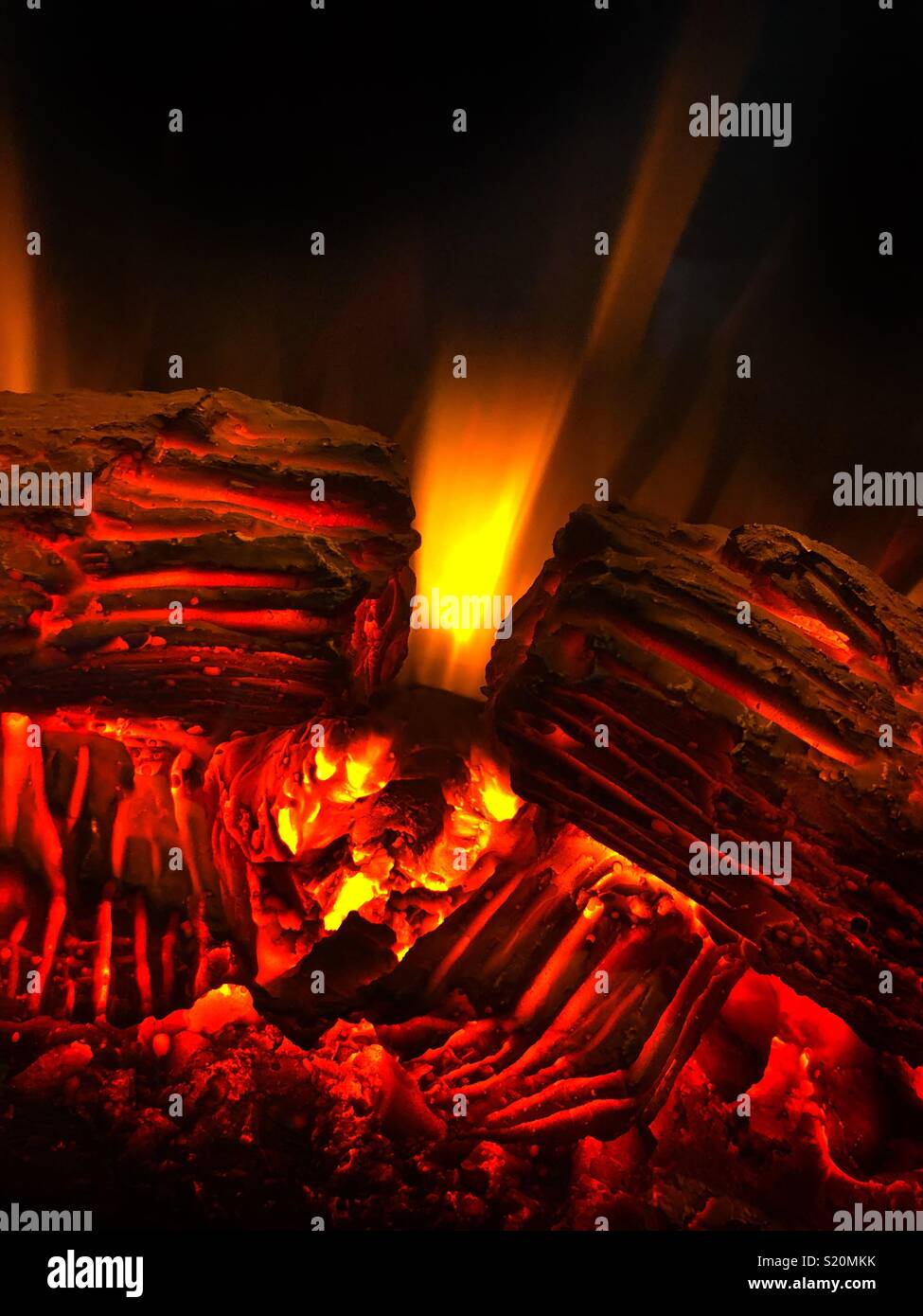 Caldo rosso e giallo fiamme contro uno sfondo scuro in un caminetto finto riscaldatore. - Immagine stock catturata con smartphone