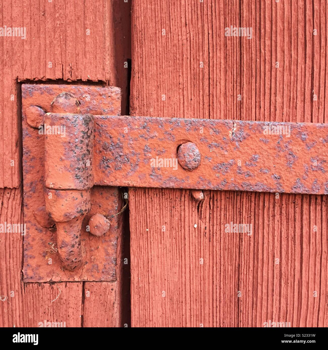 Rosso ruggine dipinta vecchia cerniera su una porta di legno - Immagine stock catturata con smartphone