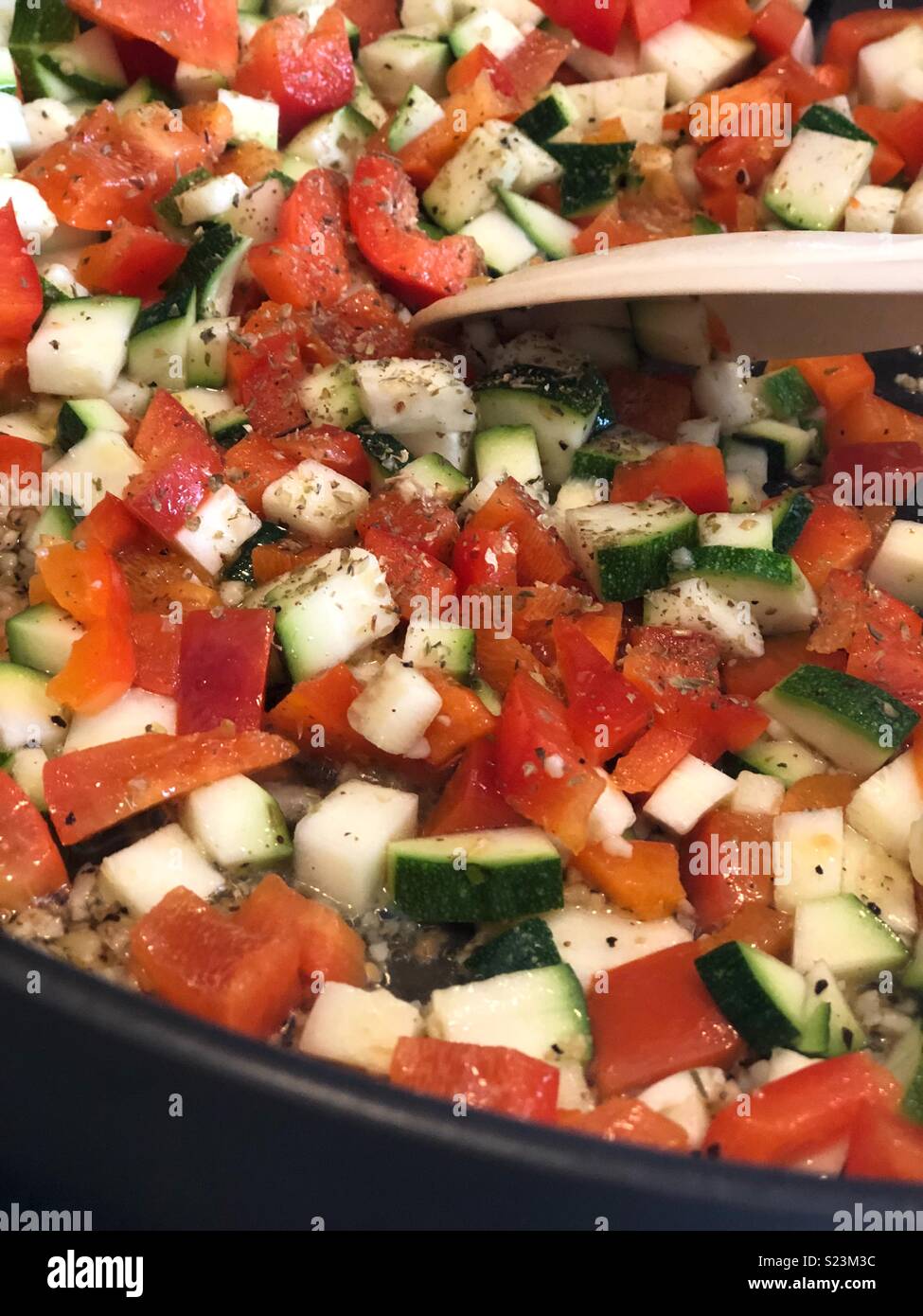 Peperoni rossi tagliati e zucchine sautéing in una padella Foto Stock