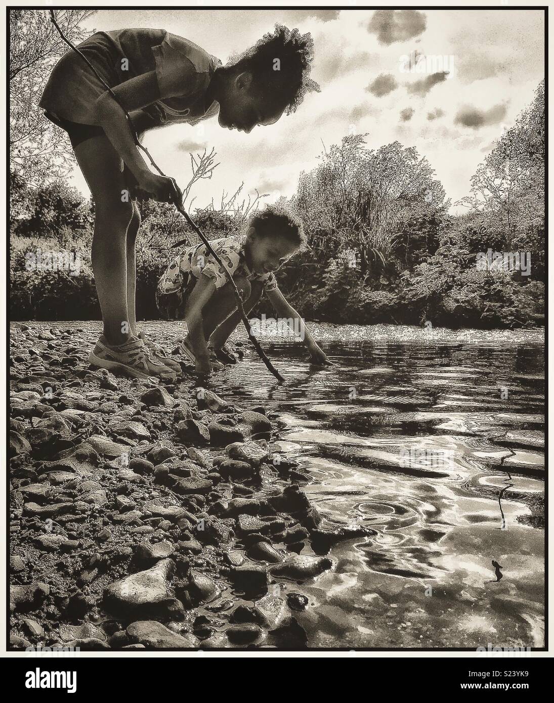 I bambini ad esplorare una riva di un fiume Foto Stock