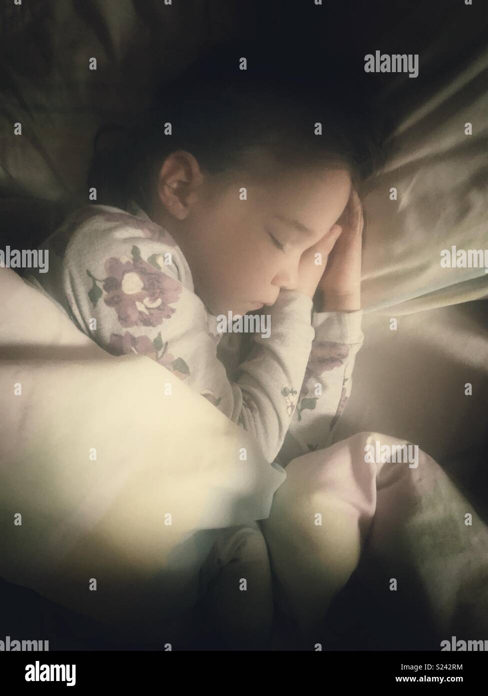 Autentica immagine di 5 anno vecchia ragazza dorme nel letto con la luce del mattino sulla faccia Foto Stock