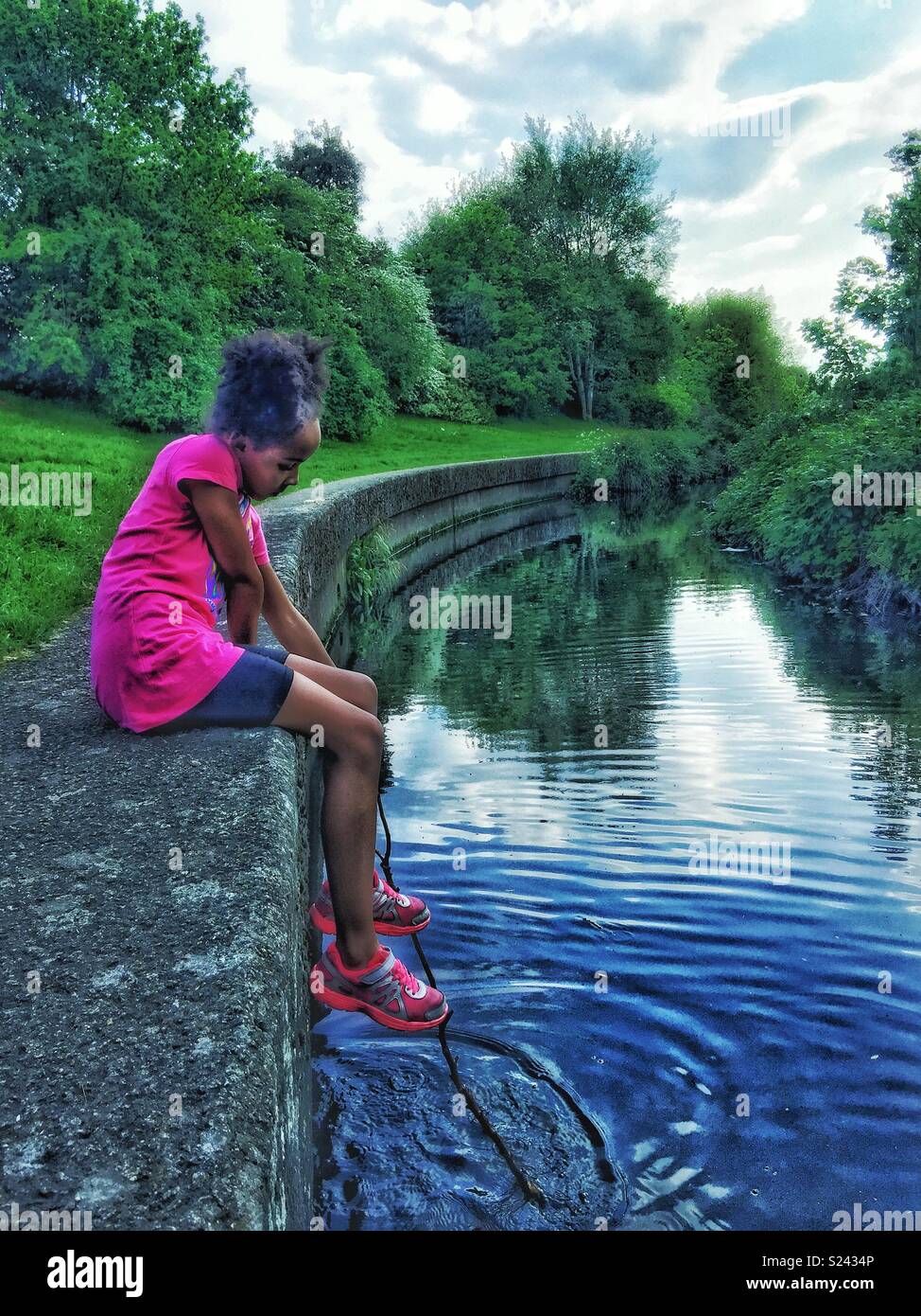 Una ragazza da sola sulla riva del fiume. Foto Stock