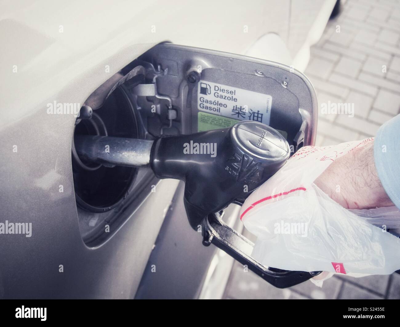 Il rifornimento di carburante della macchina self service con un guanto di plastica - Immagine stock catturata con smartphone