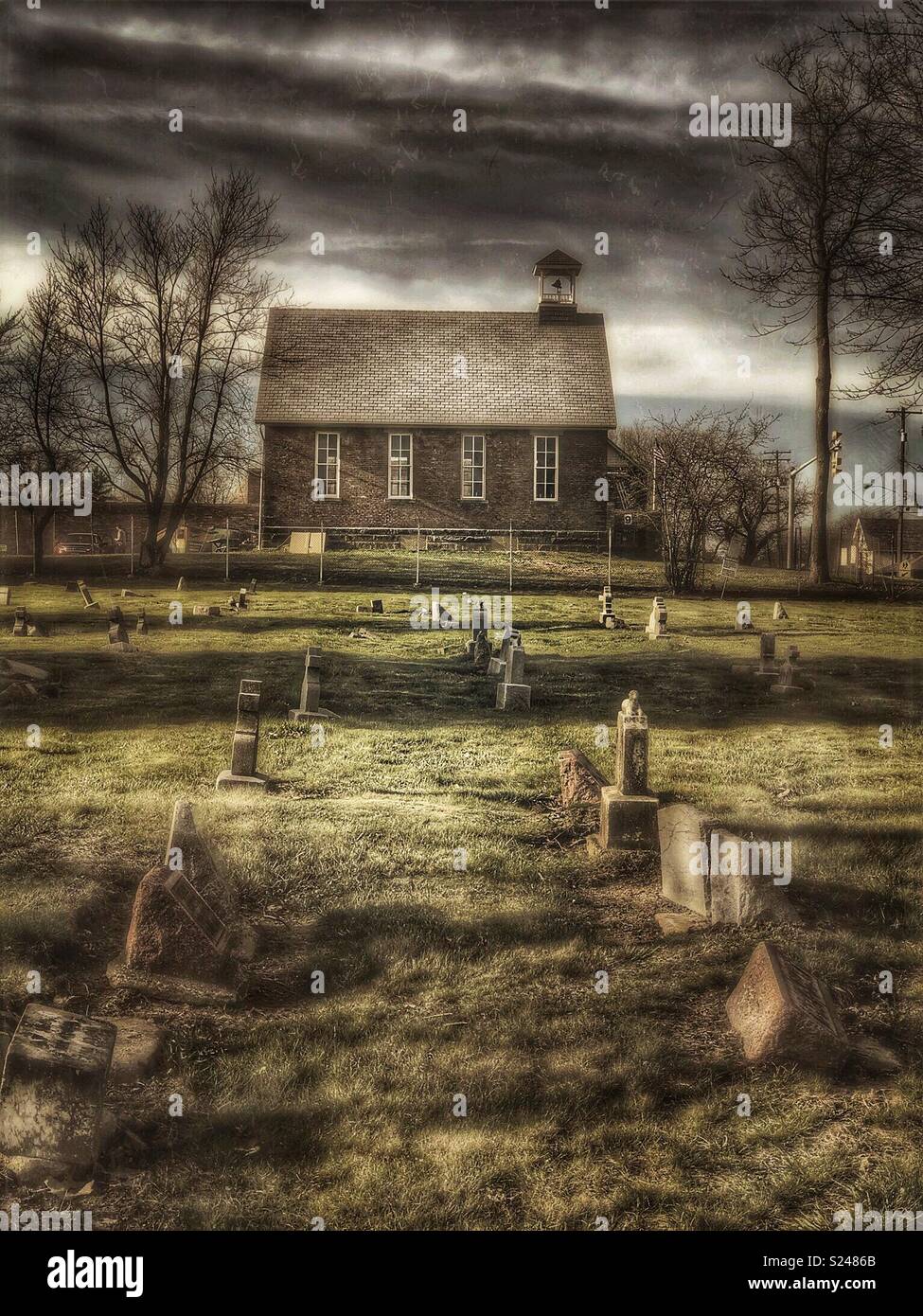 Old schoolhouse con cimitero in primo piano Foto Stock