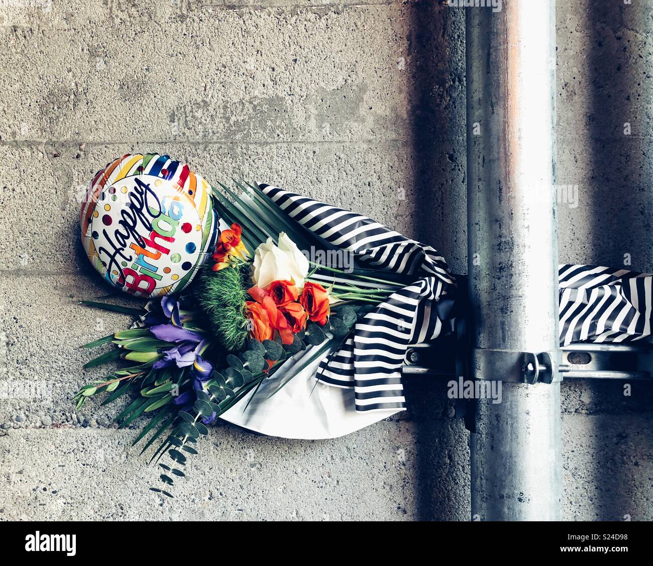 Buon compleanno bouquet con palloncino attaccato dietro il tubo di metallo Foto Stock