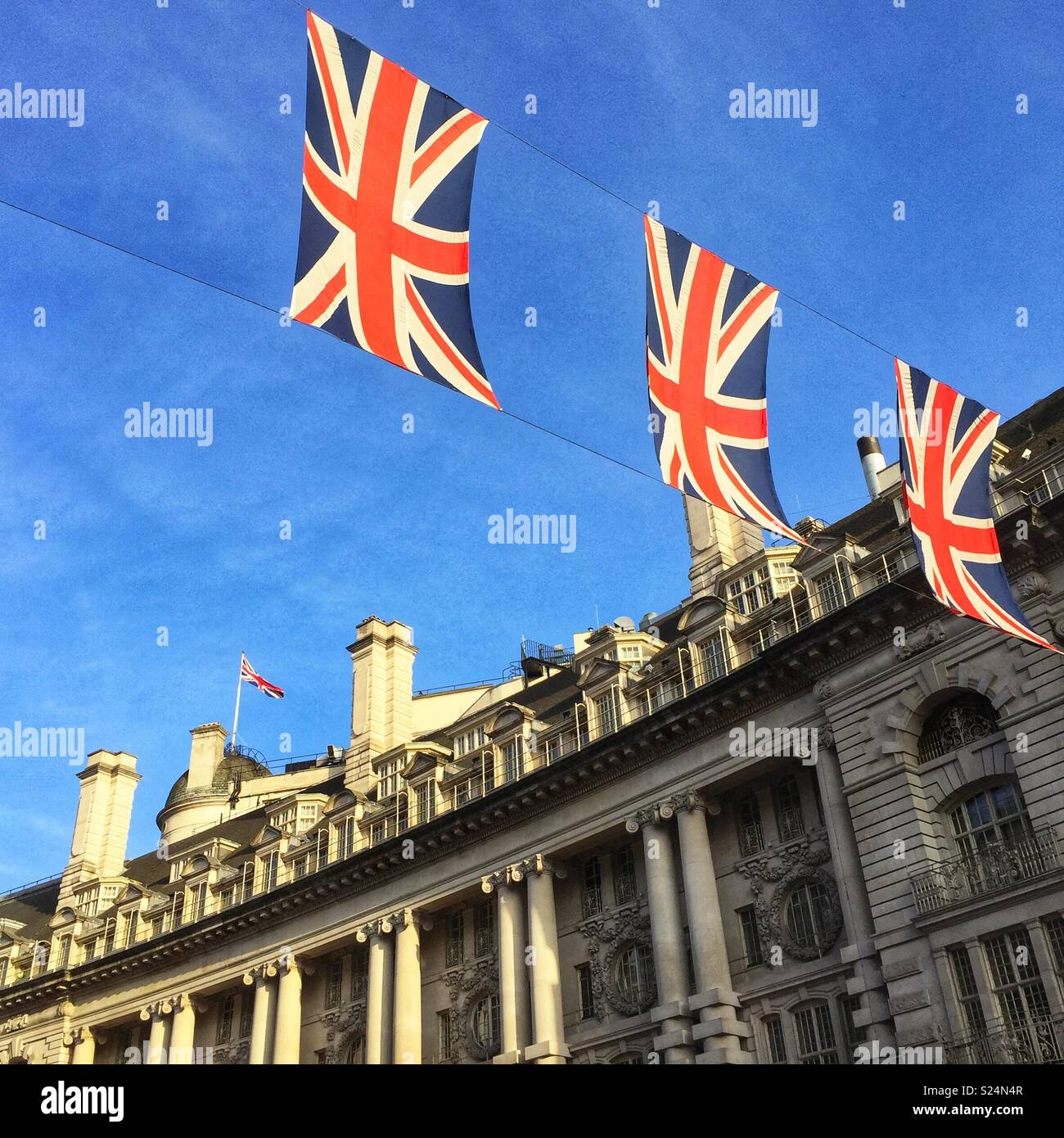 Un banner di tre Union Jack appeso bandiere attraverso Regents Street, Londra, Regno Unito. Foto Stock