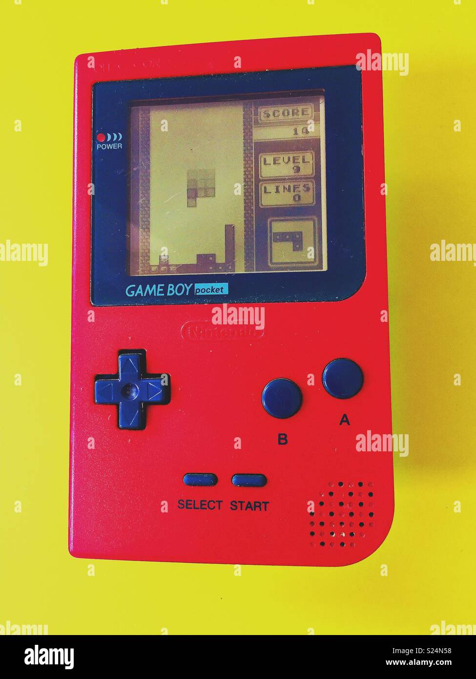 Red Game Boy Pocket contro di colore giallo brillante background con Tetris vintage retrò classico gioco sullo schermo. Foto Stock