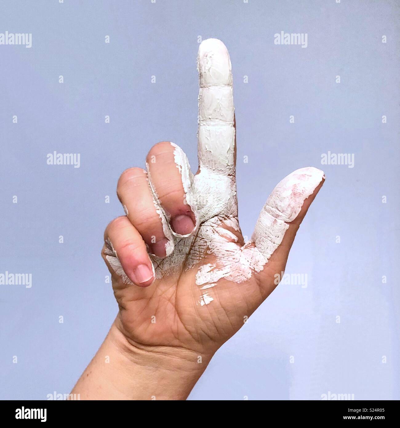 Una mano ricoperto in vernice bianco rivolto verso l'alto con il dito indice Foto Stock