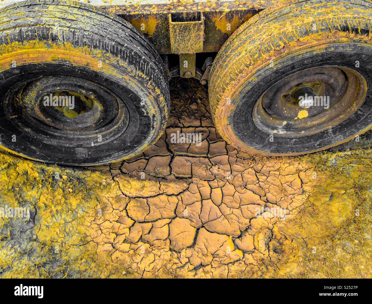 Colorpop giallo di secche, incrinato foro di fango e gli pneumatici del rimorchio Foto Stock