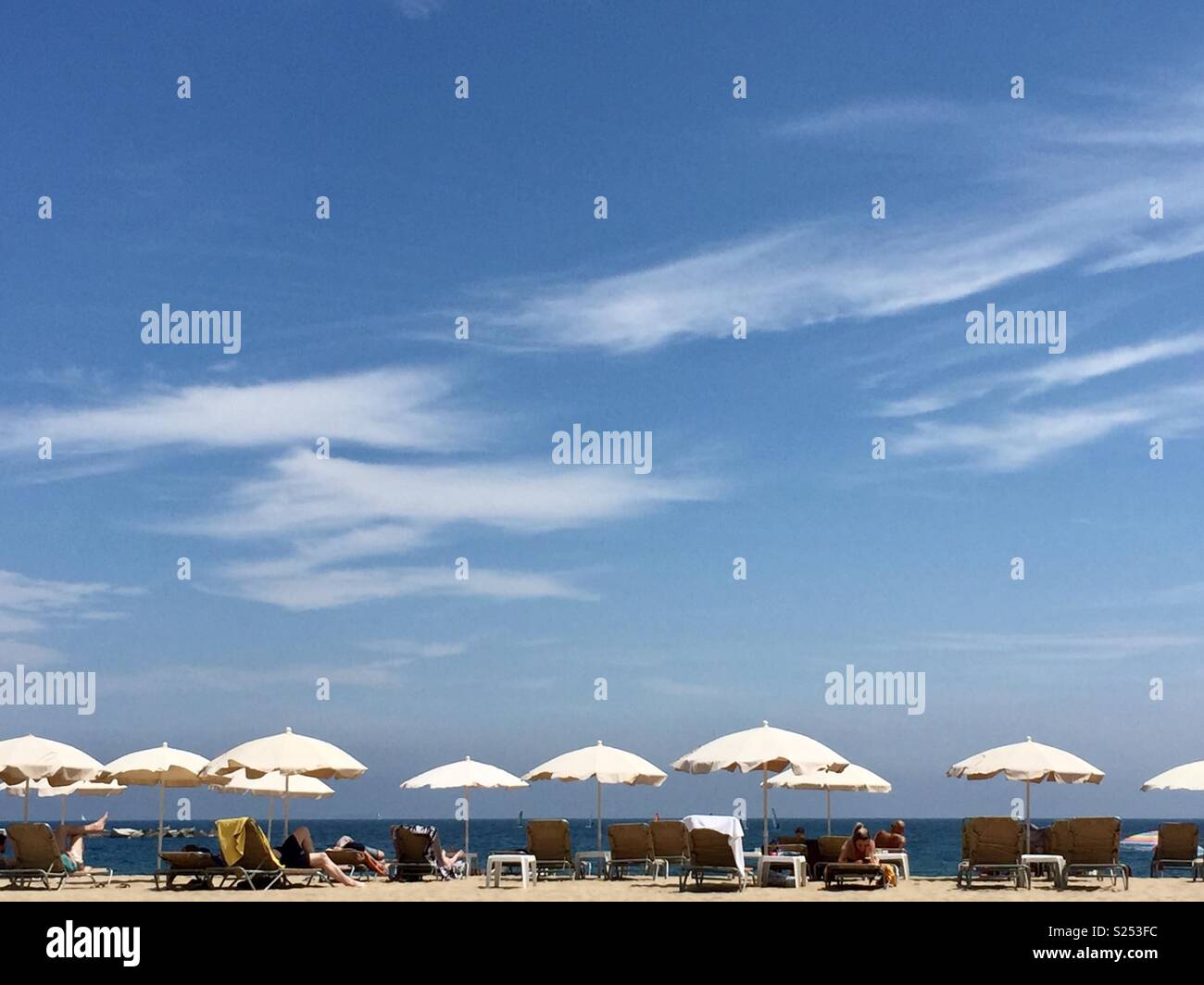 White ombrelloni sulla spiaggia di sabbia con cielo blu Foto Stock