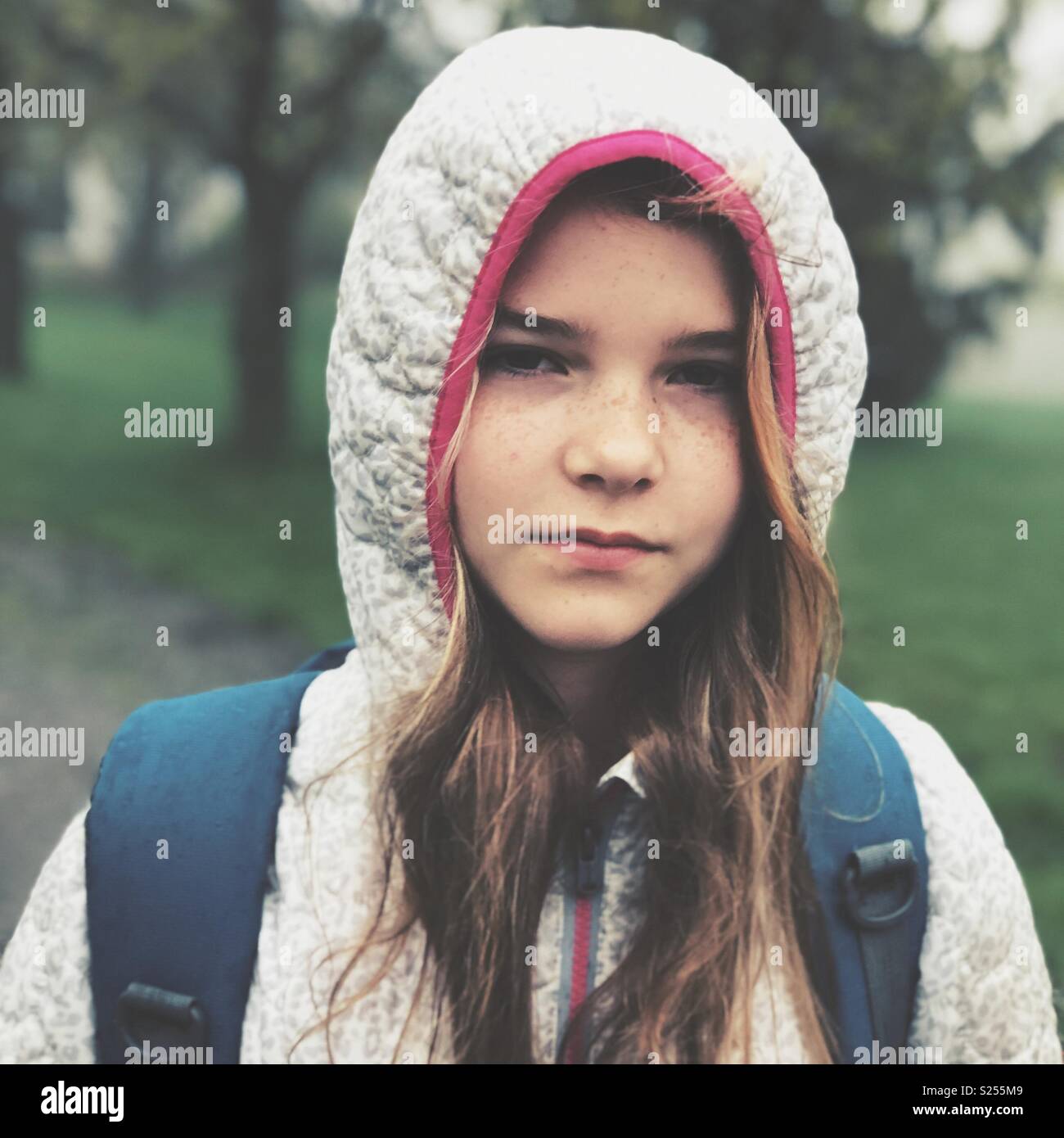 Ritratto di una scolaretta con capelli lunghi e espressione seria in piedi al di fuori Foto Stock