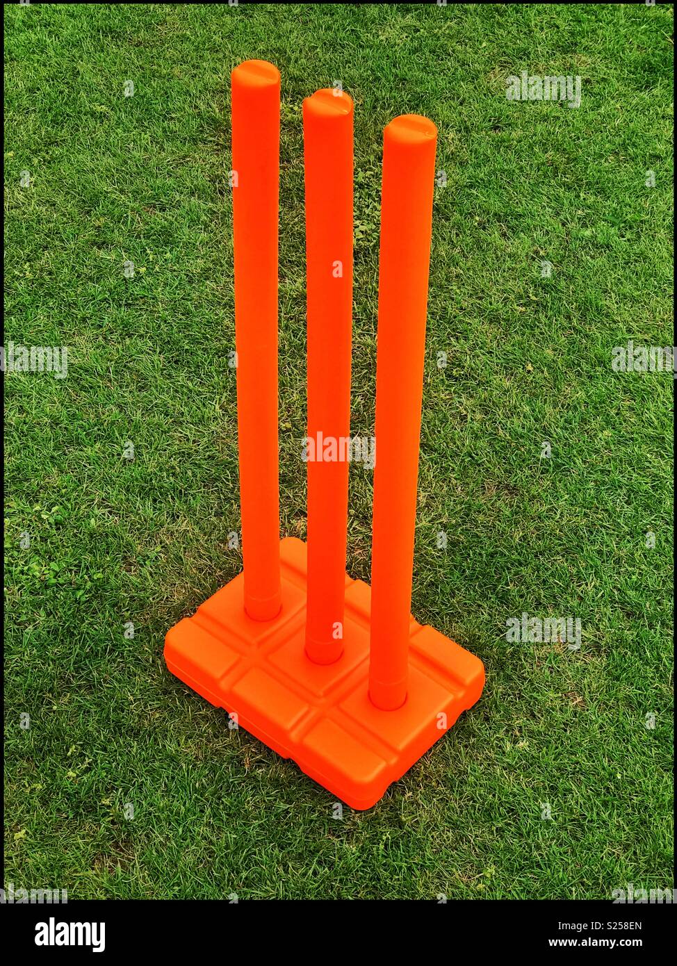 3 di plastica arancione monconi di cricket sedersi in una base pronta per i bambini a giocare al gioco del cricket. È estate ed è il tempo per godersi il cricket. Credito foto - © COLIN HOSKINS. - Immagine stock catturata con smartphone