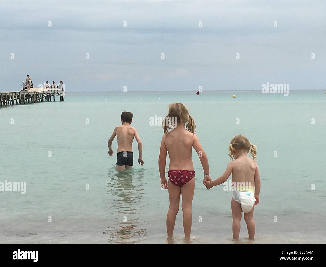 I fratelli paddling in mare e sorelle tenendo le mani in un oceano di calma Foto Stock