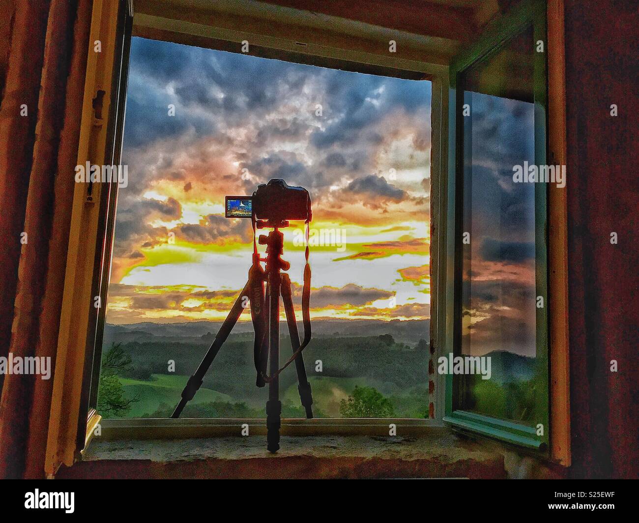 Canon 80D su Benro FGP18un treppiede, prendendo la foto di un tramonto mozzafiato, incorniciato entro una finestra aperta. Regione di Cantal, Francia. - Immagine stock catturata con smartphone