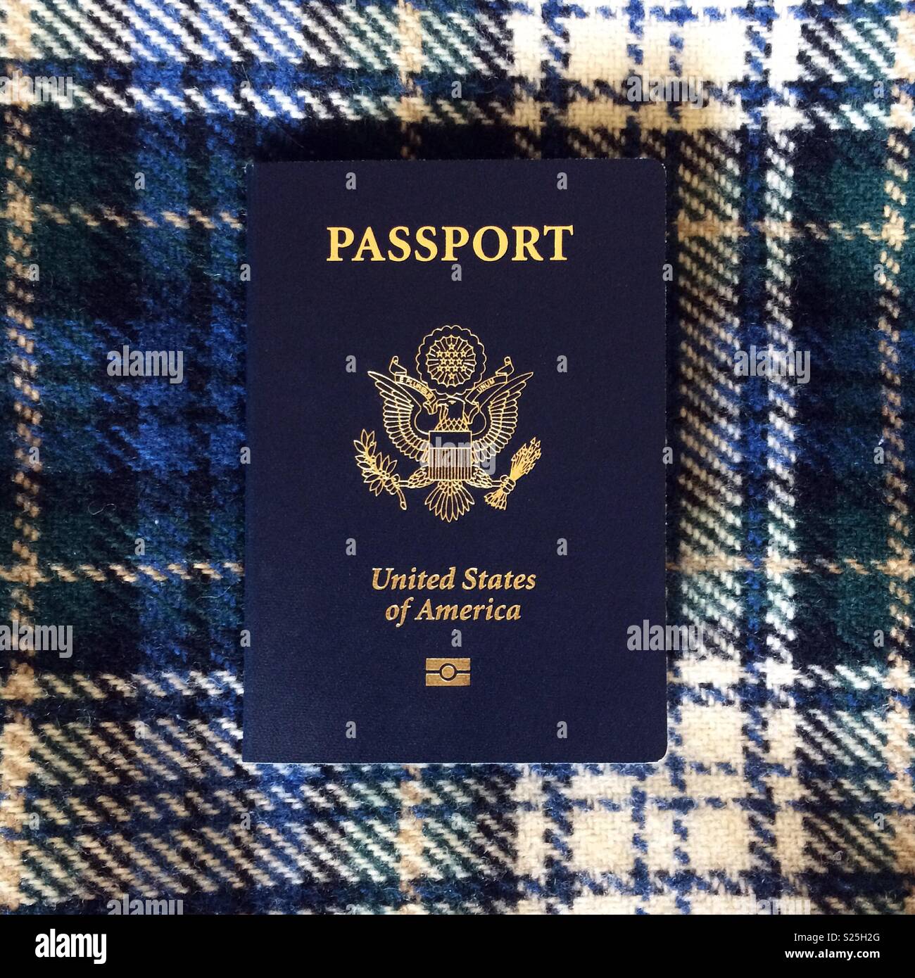 Una vista in pianta di un passaporto statunitense seduto su un tartan blu coperta Foto Stock