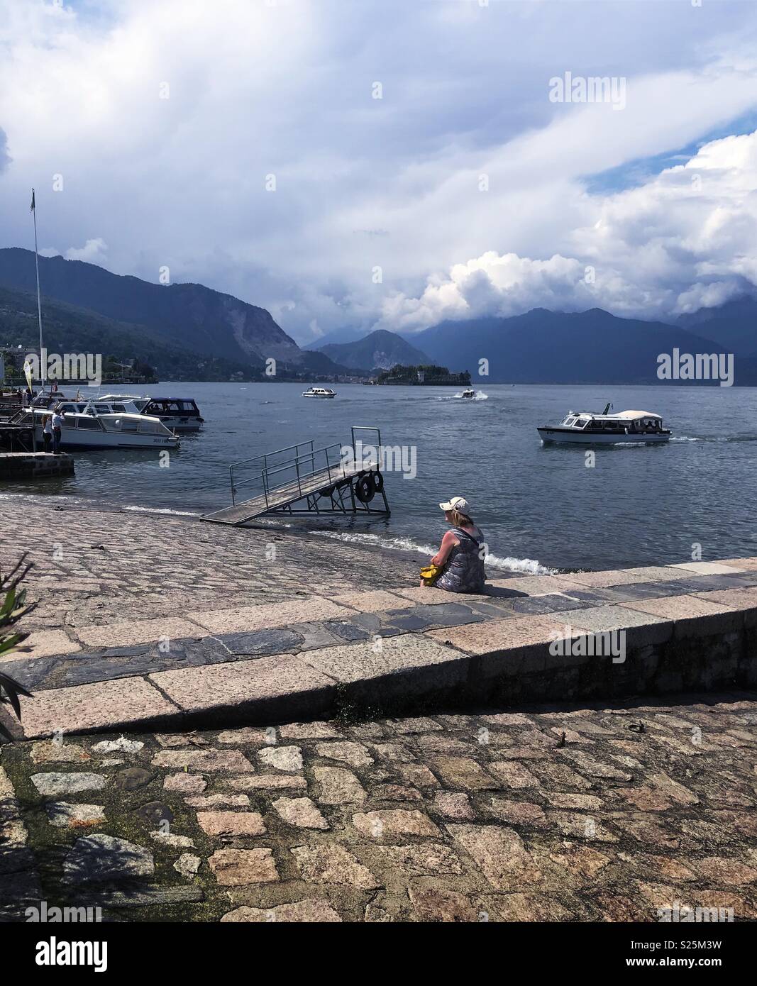 Donna seduto a guardare le barche sul lago Maggiore a Stresa, Italia. Foto Stock