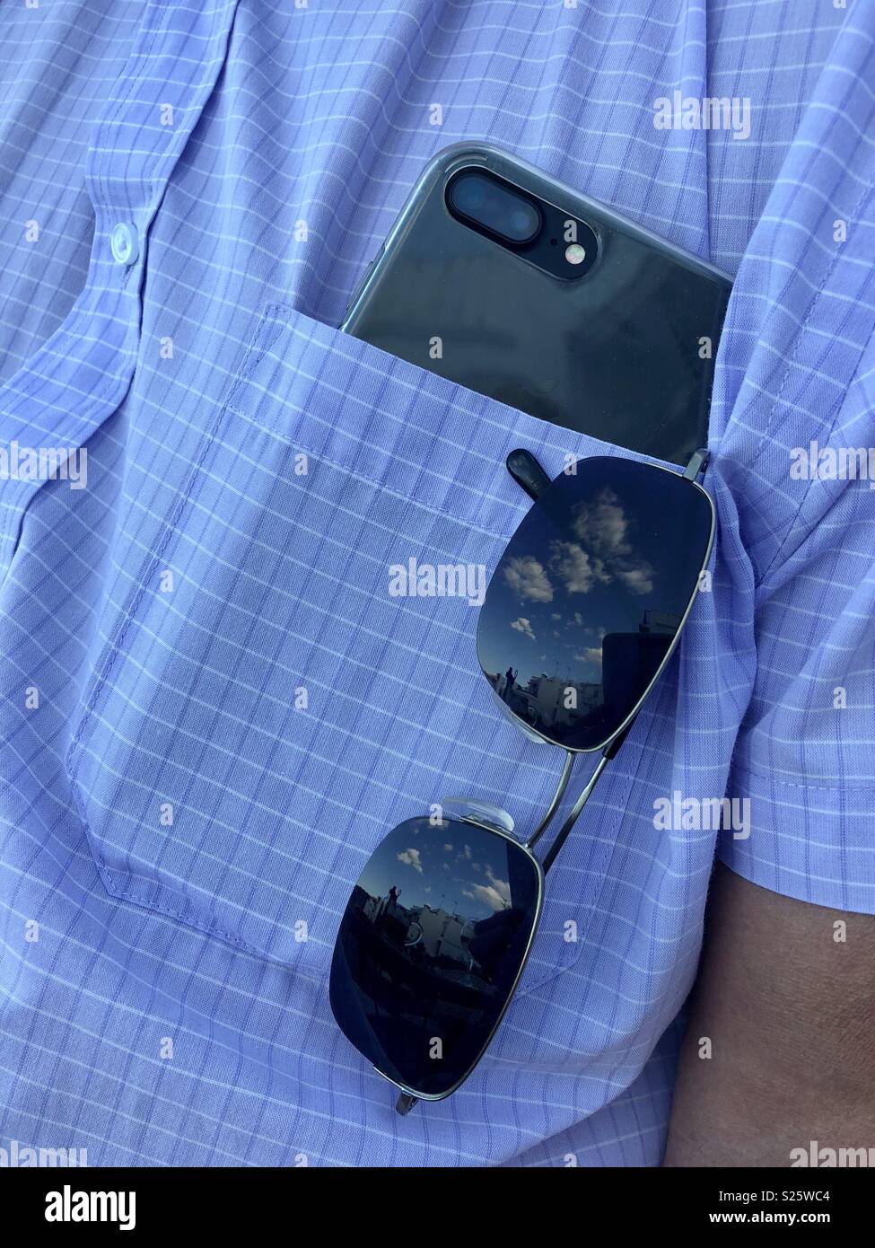 I riflessi del paesaggio sulle lenti di un paio di occhiali da sole in un uomo di tasca della camicia. Foto Stock