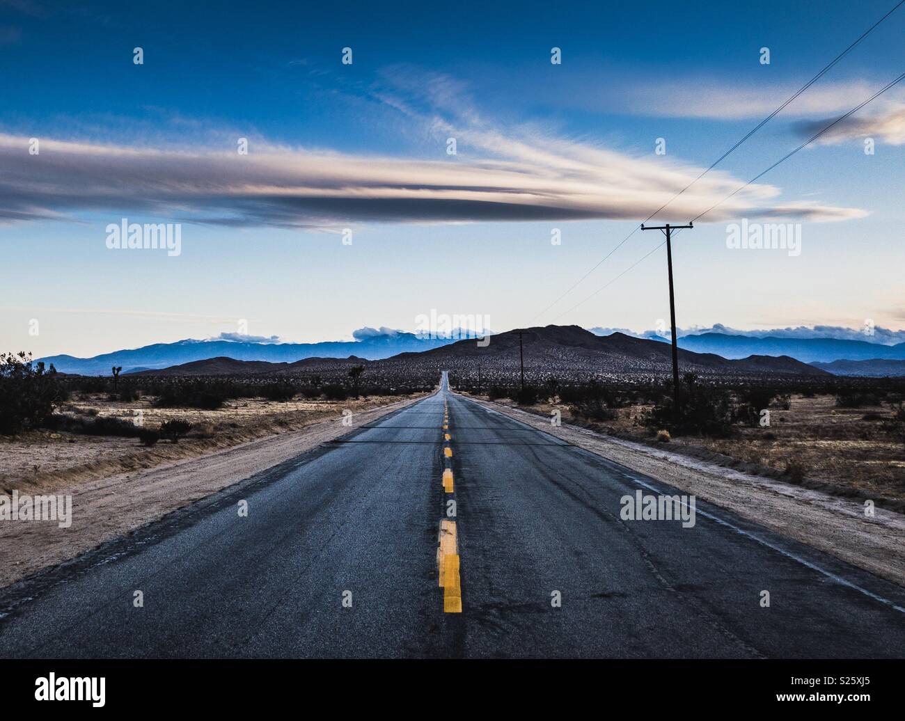 Strada nel deserto della California con drammatica nuvole e montagne. Foto Stock