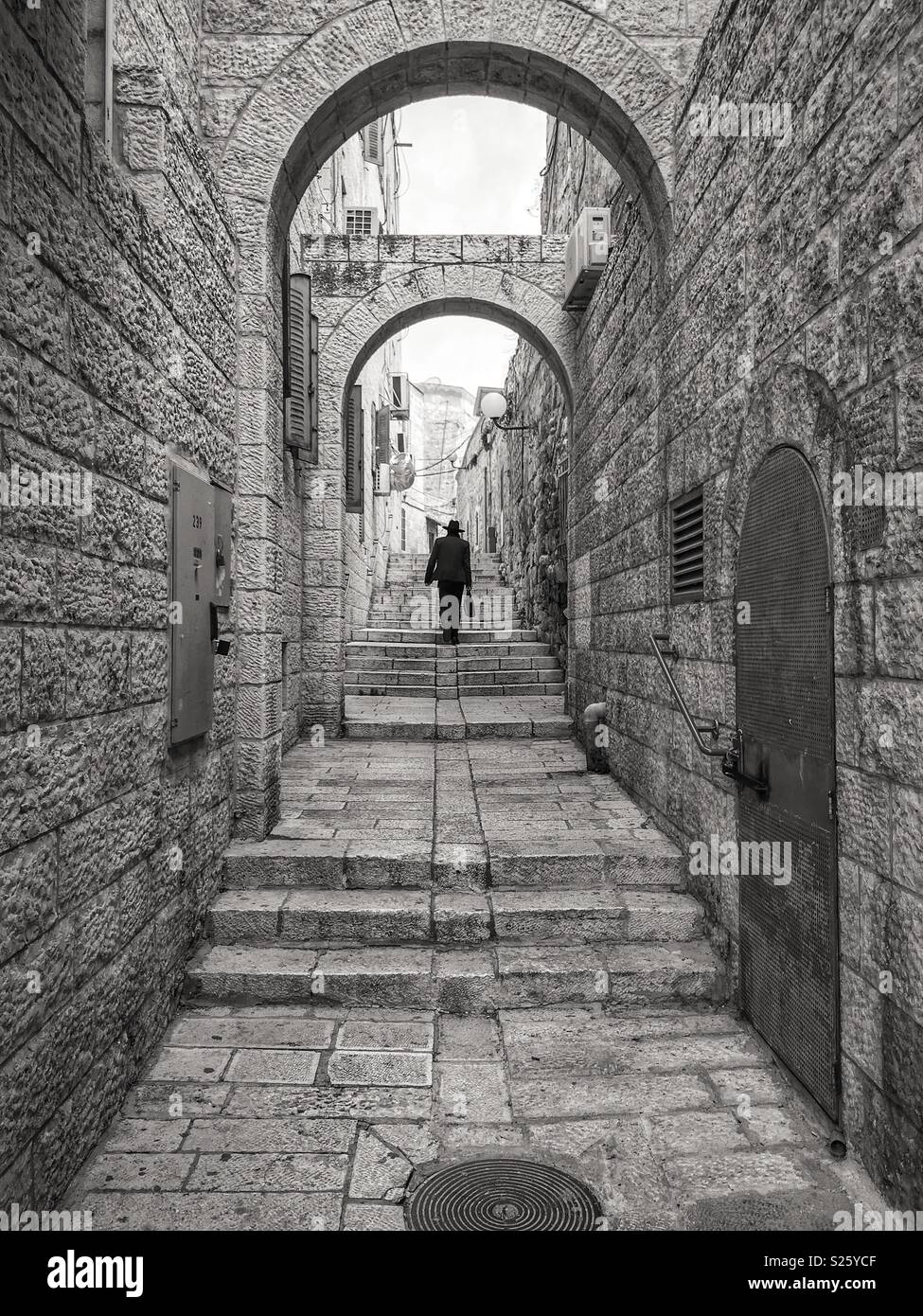 Un Ebreo uomo cammina anche se un vicolo tra edifici del quartiere ebraico della città vecchia di Gerusalemme, Israele. Foto Stock