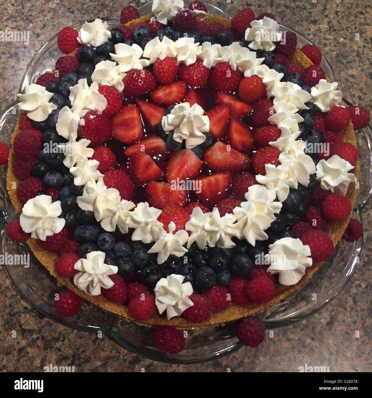 Frutti di bosco torta di anniversario con la panna montata in un vetro piatto floreale. Un delizioso e colorato dessert - Immagine stock catturata con smartphone