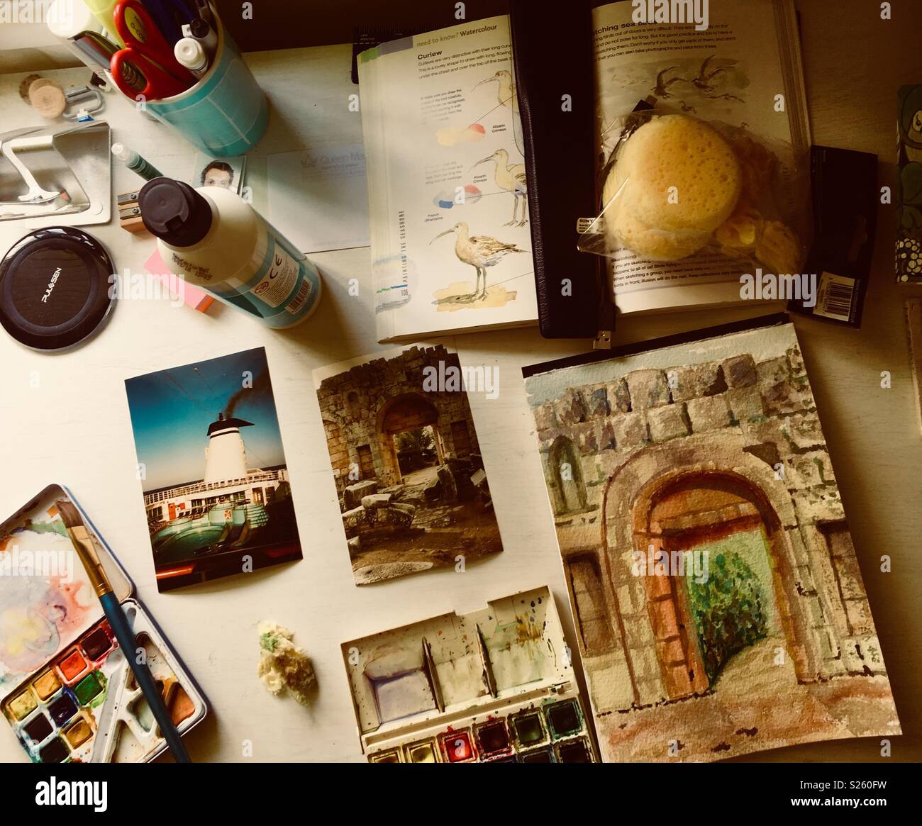 Un artista della scrivania con vernici, pittura, foto e altre attrezzature artistiche. Foto Stock